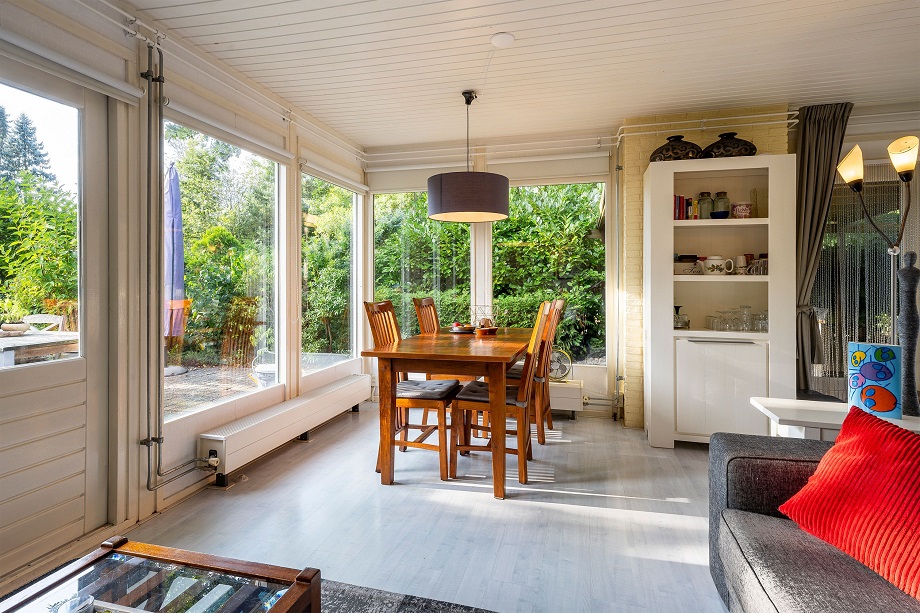 Grote woonkamer met ramen op privé tuin bij vakantiehuis Drenthe